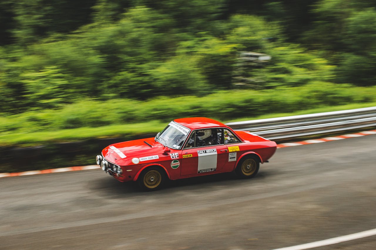 A red sports car driving down a road